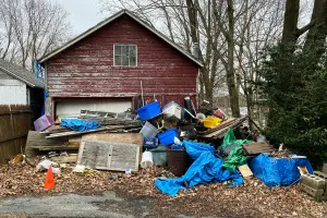 A pile of junk outside a detached garage. Contact Mike & Dads's Hauling for your junk removal needs in Portland.
