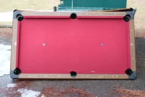 aerial view of an old red pool table near a dumpster