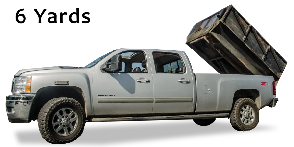 A grey pickup truck with its large black dump bed raised for Mike & Dad's Hauling's 6 Yard Truck Loads.
